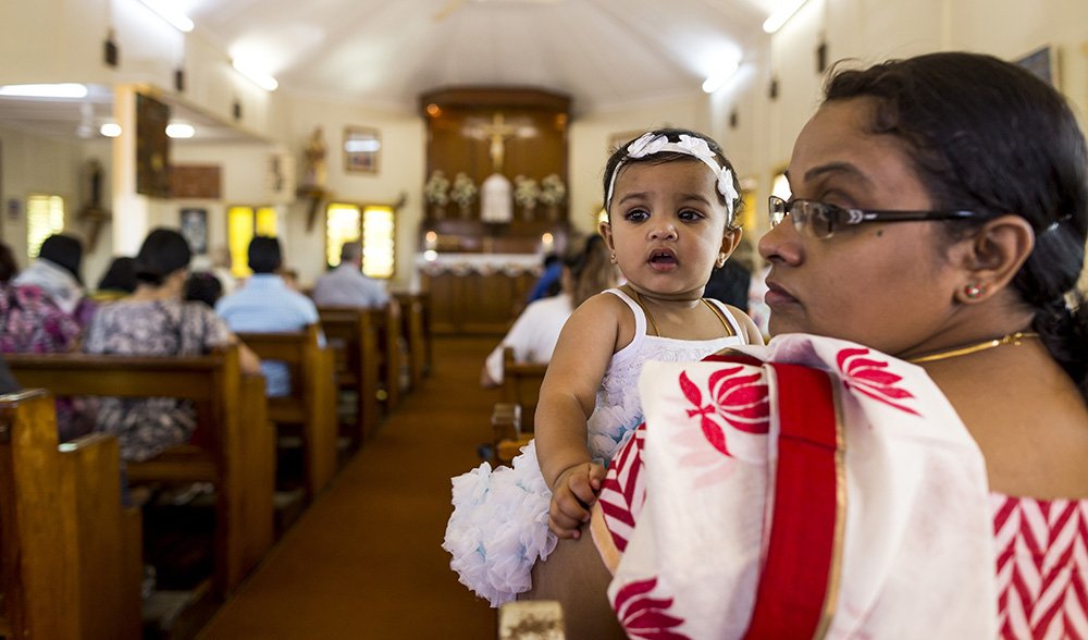 Anu shaji holds baby Tessa for Sunday morning Worship.