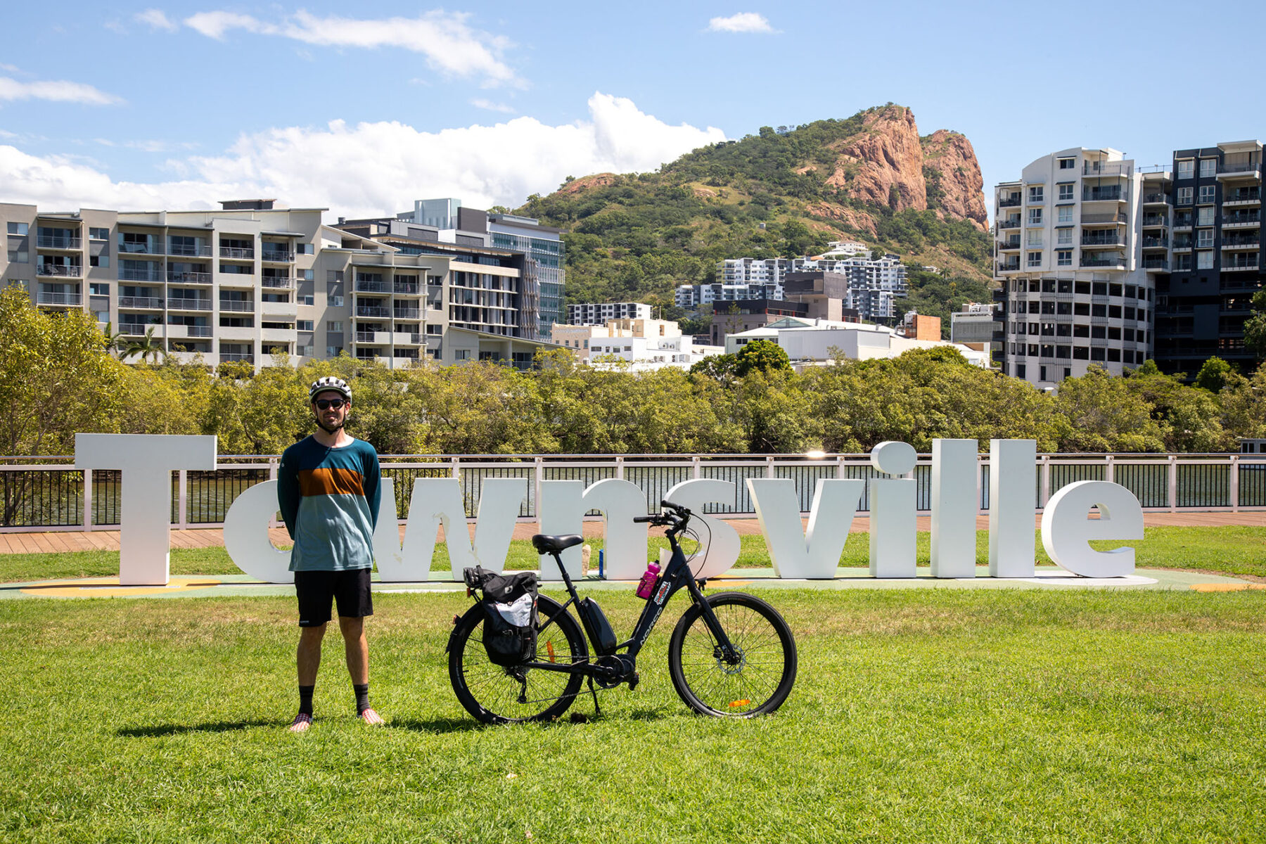 A cyclist and his bike in front of the Townsville sign